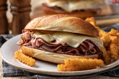 Sıcak jambonlu ve peynirli sandviç ve tabakta patates kızartması.