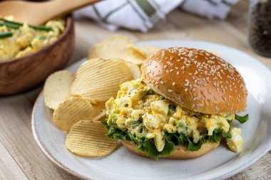 Tabakta susamlı çörek ve marullu yumurtalı sandviç.