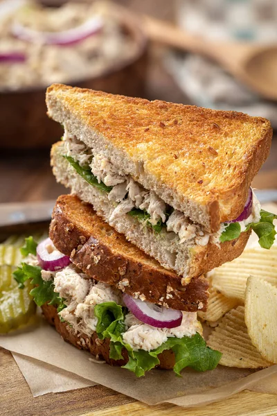 Tuna salad sandwich with lettuce and red onion on toasted whole wheat bread cut in half and stacked