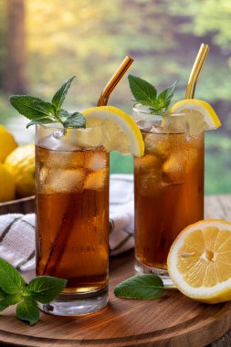 İki bardak buzlu çay ve bir dilim limon ve kırsal arka plandaki tahta tepside nane.