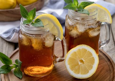İki bardak limon dilimli buzlu çay ve tahta tepside nane. 