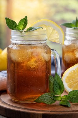 Limon dilimli bir bardak buzlu çay ve kırsal arka planı olan tahta tepside nane şekeri.