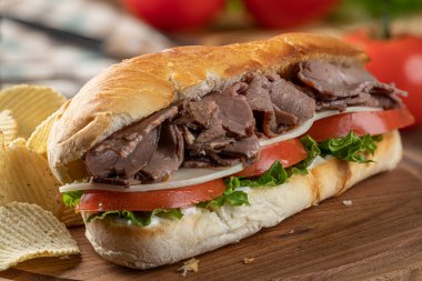 Biftekli, peynirli, domatesli ve marullu sandviç ve patates cipsli sandviç.
