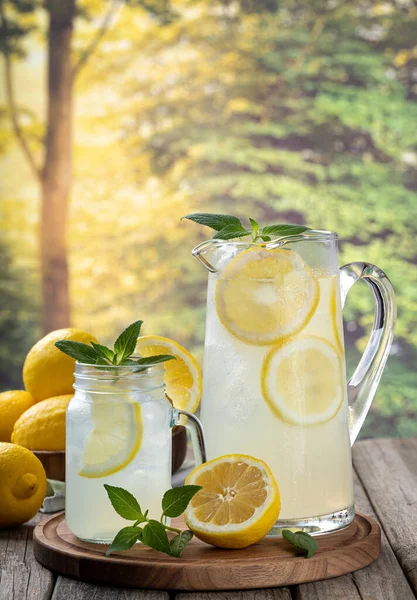 Limon dilimleri ve nane şekerli bir sürahi limonata kırsal arka planda eski ahşap bir masada.