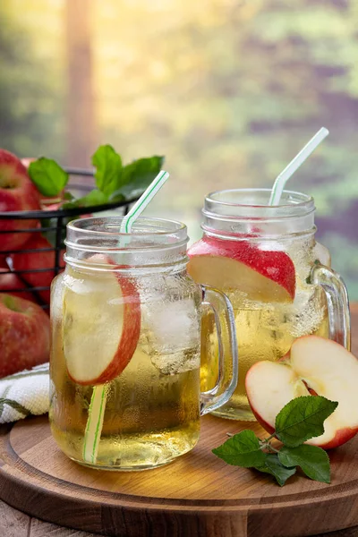 Kırsal kesimde, tahta bir tabakta iki bardak soğuk elma suyu.