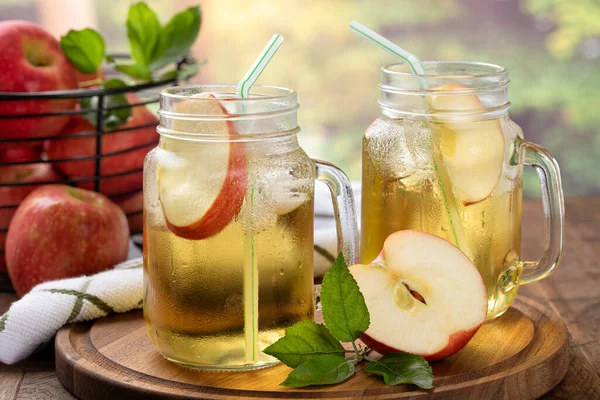 Kırsal kesimde, tahta bir tabakta iki bardak soğuk elma suyu.