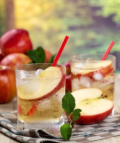 Elma suyunu elma dilimiyle tazelemek ve yaz arkaplanlı bir bardakta buz.