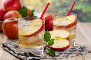 Elma suyunu elma dilimiyle tazelemek ve yaz arkaplanlı bir bardakta buz.