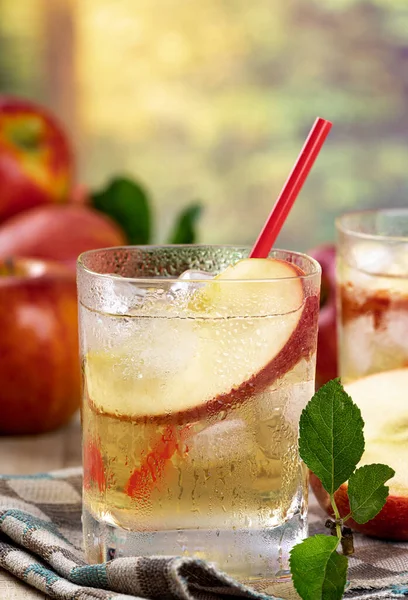 Elma suyunu elma dilimiyle tazelemek ve yaz arkaplanlı bir bardakta buz.