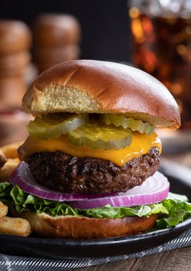 Siyah tabakta turşulu çizburger, soğan, marul ve patates kızartması.