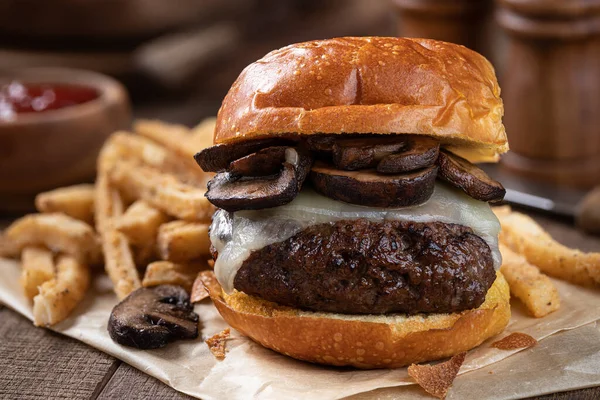 Closeup of cheeseburger with mushrooms on toasted bun with french fries