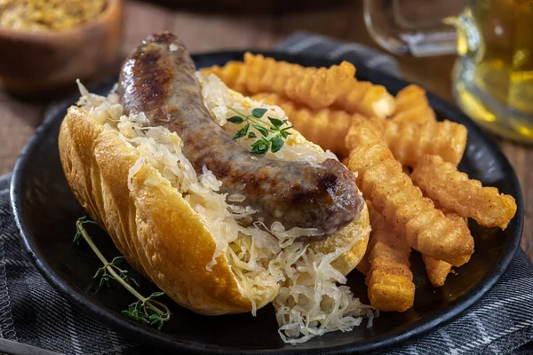 Closeup Grilled Bratwurst Sauerkraut Bun French Fries Black Plate — Stock Fotó