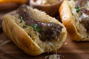 Closeup of bratwurst and sauerkraut on a bun  on a wooden platter