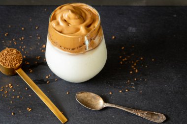 Dalgona kahvesi. Koyu arkaplanda Kore usulü buzlu kahve. Lezzetli kahvaltı için şekerli ve suyla çırpılmış hazır kahve. Çok modaya uygun bir içki..