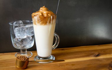 Dalgona kahvesi. Koyu arkaplanda Kore usulü buzlu kahve. Lezzetli kahvaltı için şekerli ve suyla çırpılmış hazır kahve. Çok modaya uygun bir içki..