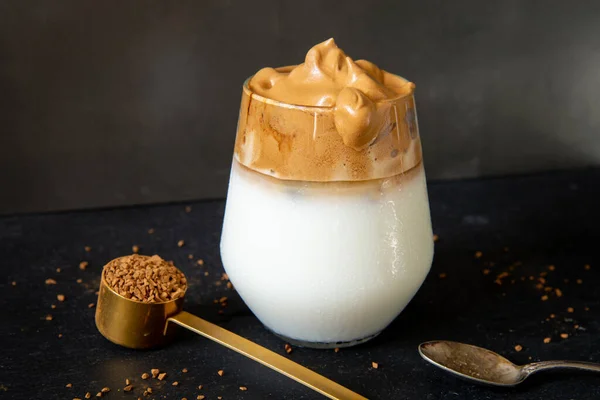 Dalgona kahvesi. Koyu arkaplanda Kore usulü buzlu kahve. Lezzetli kahvaltı için şekerli ve suyla çırpılmış hazır kahve. Çok modaya uygun bir içki..