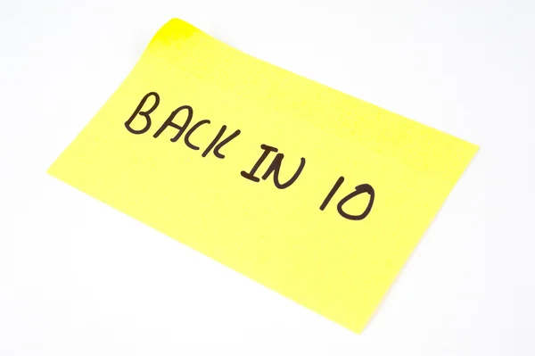 'Back In 10' escrito em uma nota pegajosa amarela — Fotografia de Stock