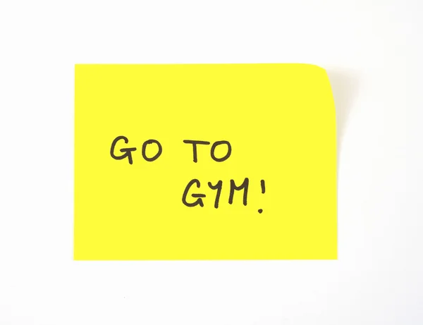 'Go To Gym' skrevet på en gul klæbrig note - Stock-foto
