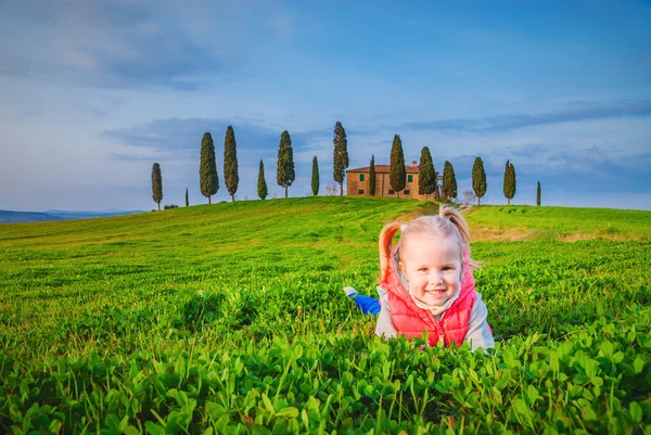 Little girl smiling and playing on a meadow in front of a Tuscan — Stock Photo, Image