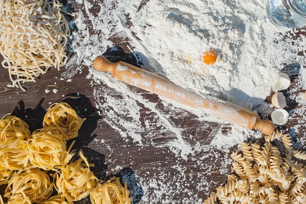 Pasta egg in flour and a rolling pin. — Stock Photo, Image