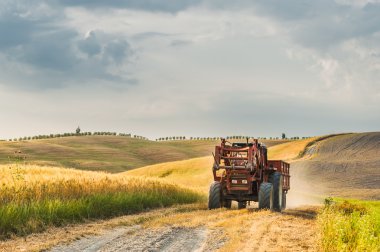 Tuscany, İtalya 'da tarlalarda römorklu bir traktör.