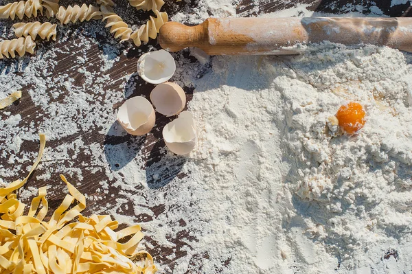 Pasta egg in flour and a rolling pin. — Stock Photo, Image