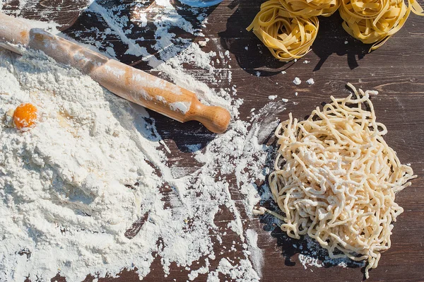 Pasta egg in flour and a rolling pin. — Stock Photo, Image