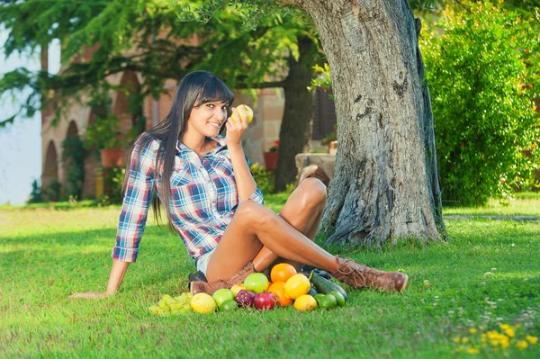 Beautiful woman on the green grass eaten fruits — Stock Photo, Image