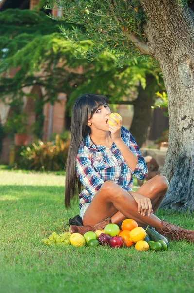 Beautiful woman on the green grass eaten fruits — Stock Photo, Image