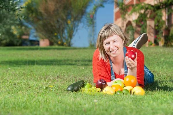 Woman with fruits on green grass — Stock Photo, Image