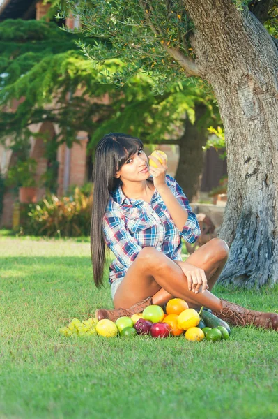 Beautiful woman on the green grass eaten fruits — Stock Photo, Image