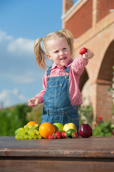 Dívka jíst barevné ovoce mimo — Stock fotografie