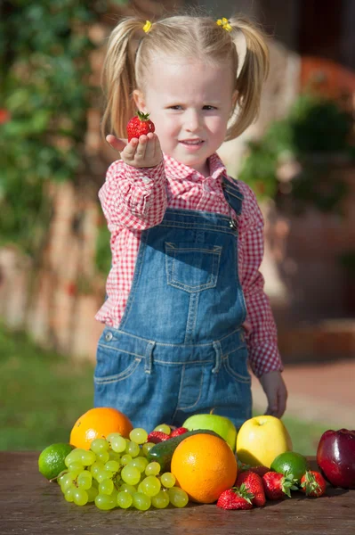 Dívka jíst barevné ovoce mimo — Stock fotografie