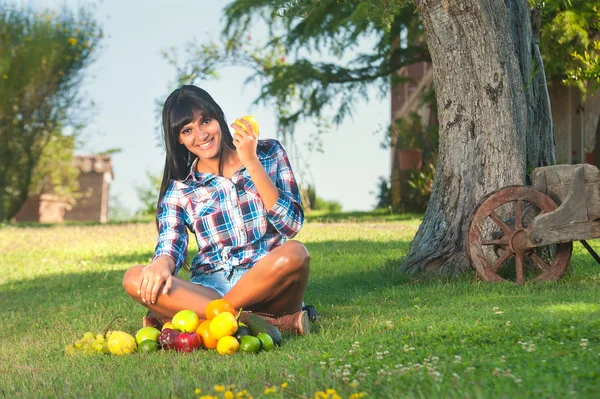 Schöne Frau auf dem grünen Gras gegessen Früchte — Stockfoto