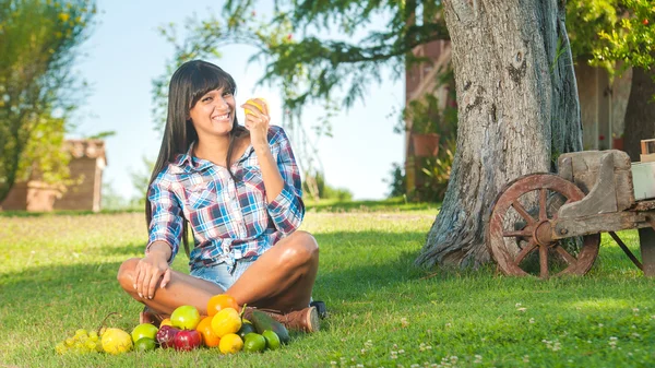 Beautiful woman on the green grass eaten fruits — Stock Photo, Image