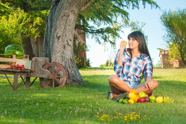 Beautiful woman on the green grass eaten fruits — Stock Photo, Image