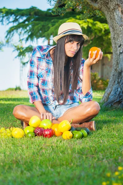 Beautiful woman on the green grass eaten colors fruits — Stock Photo, Image