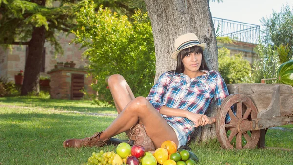 Schöne Frau auf dem grünen Gras gefressen Farben Früchte — Stockfoto