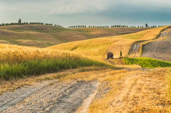 Tuscany, İtalya 'da tarlalarda römorklu bir traktör. — Stok fotoğraf