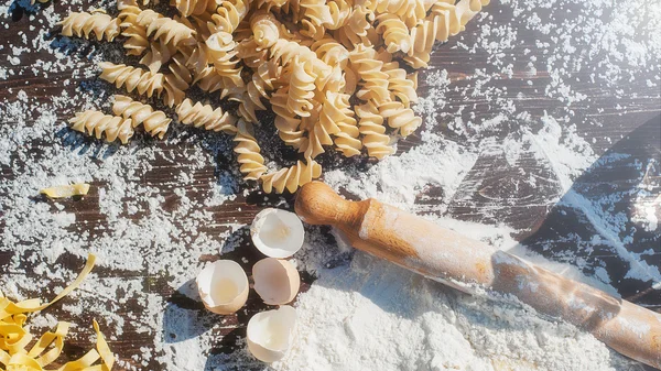 Pasta egg in flour and a rolling pin. — Stock Photo, Image
