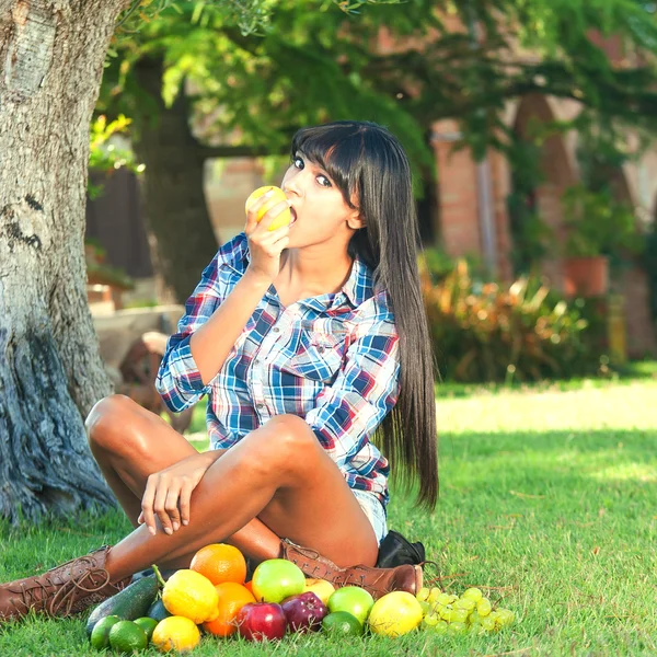 Beautiful woman on the green grass eaten fruits — Stock Photo, Image