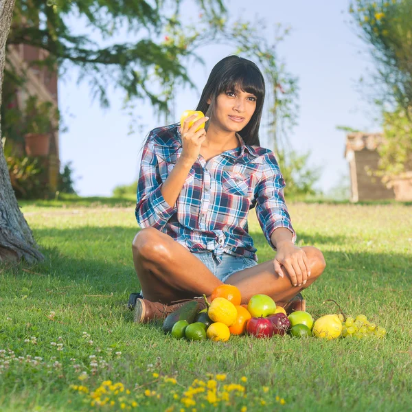 美丽的女人，在绿色的草地上吃水果 — 图库照片