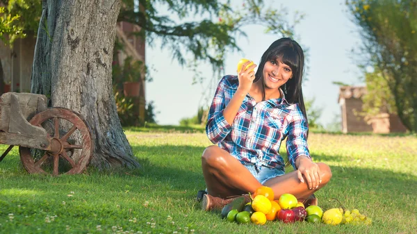 Vacker kvinna på det gröna gräset ätit frukter — Stockfoto