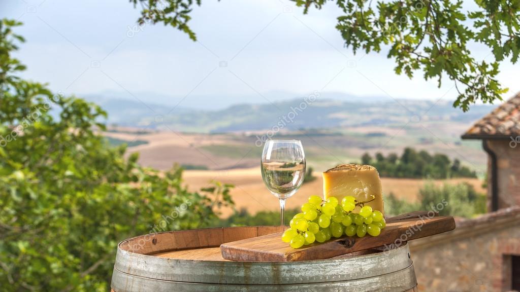 Cheese and grapes on a barrel in the Tuscan landscape Italy