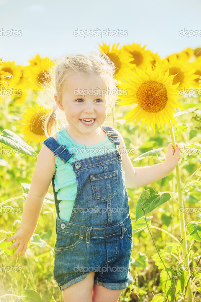 Beautiful girl plays with the sunflowers