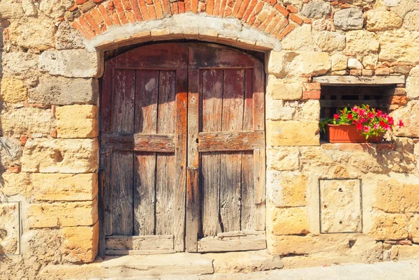 Staré zdi a dveře zdobené květinami v monteriggioni, tus — Stock fotografie