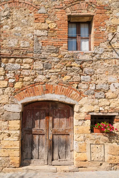 Старые стены и двери, украшенные цветами в Monteriggioni, Тус — стоковое фото