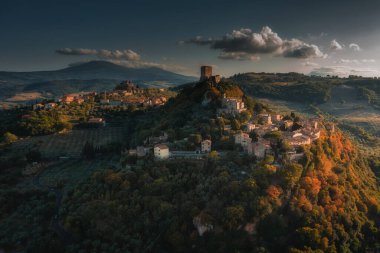 İnsansız hava aracı İtalya 'da gün batımında Rocca d' Orcia üzerinde uçuyor.