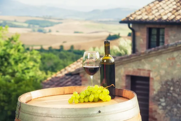 Bottiglia di vino rosso e vetro su botte di legno sullo sfondo di — Foto Stock