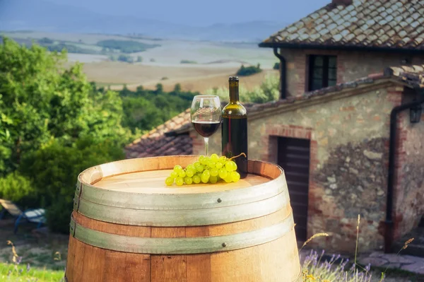 Rode wijn fles en glas op houten vat op de achtergrond van — Stockfoto